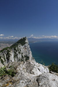 Scenic view of sea and mountains against blue sky