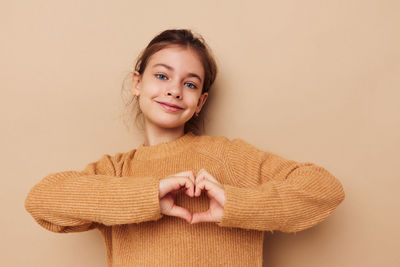 Portrait of young woman standing against pink background