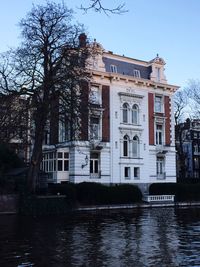 Building by lake against sky in city