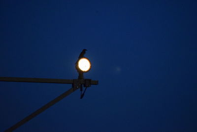 Low angle view of illuminated street light against clear blue sky