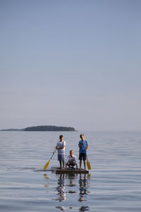 People on sea against clear sky