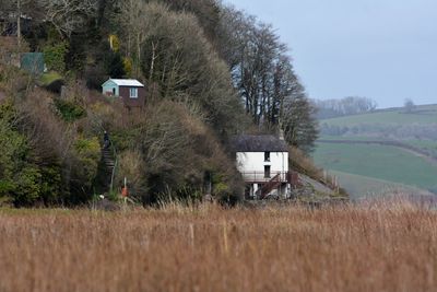 House on field by trees against sky