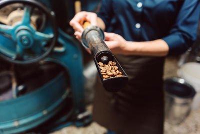 Midsection of worker showing coffee beans in sampling scoop