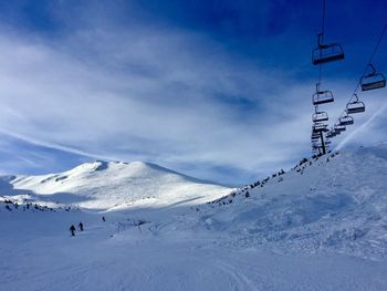 Ski lift over snowcapped mountains against sky