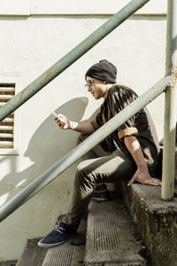 Young man surfing net through smart phone sitting on steps