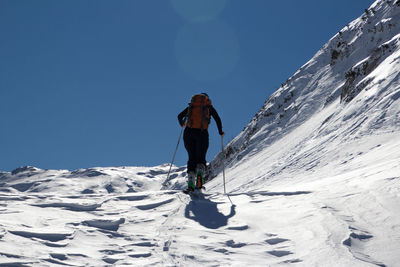 Low angle view of woman walking on snowcapped mountain against sky