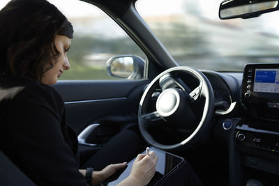 Businesswoman using tablet pc in driverless car