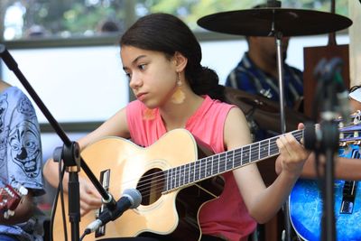 Teenage girl playing guitar on stage