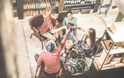 High angle view of smiling friends raising toast while sitting in restaurant