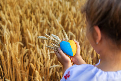 Cute girl holding heart shape with wheat at farm