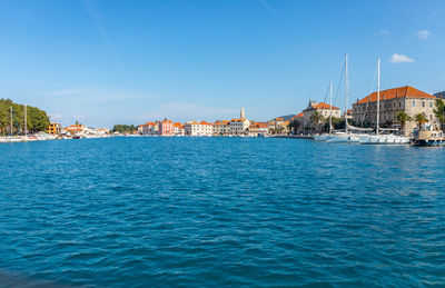 Buildings by sea against blue sky