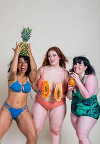 Portrait of smiling women holding fruits standing at home