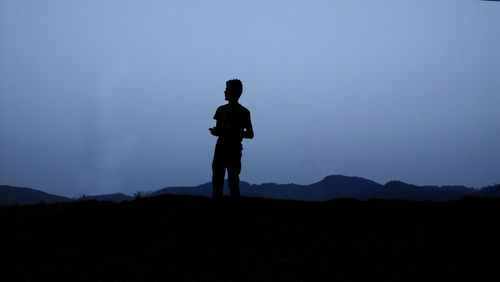 Silhouette man standing on mountain against clear sky at night