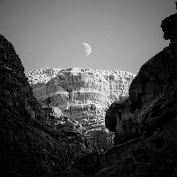 Low angle view of rock formations and moon during day