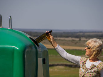 Woman with arms raised standing against sky