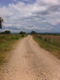 Road amidst field against sky