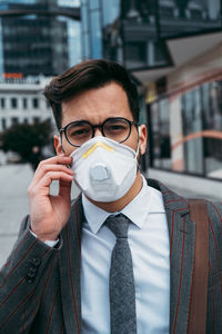 Business man standing on city street with protective face mask.