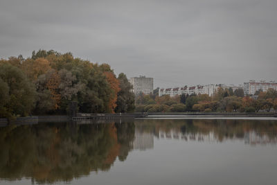 Reflection of trees and buildings in lake against sky