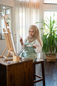 Portrait of young woman using laptop while sitting on table at home