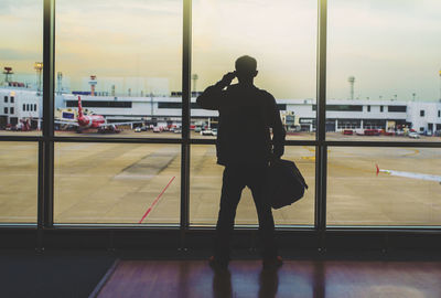 Man standing on airport runway against sky in city