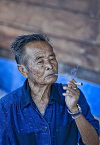 Senior man smoking cigarette while sitting outdoors