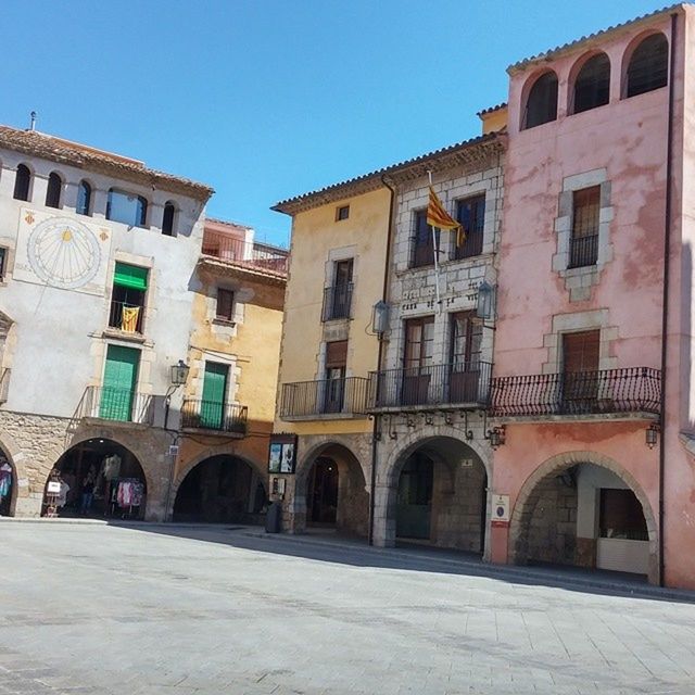 architecture, building exterior, built structure, window, clear sky, arch, residential building, building, residential structure, facade, city, street, day, sunlight, in a row, cobblestone, house, blue, outdoors, low angle view