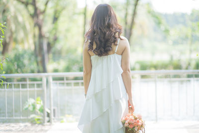 Rear view of woman with umbrella standing against plants