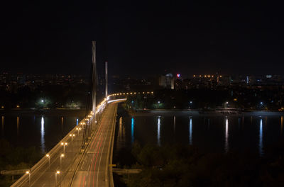 Illuminated bridge over river in city at night