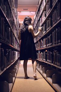 Rear view of woman walking in library