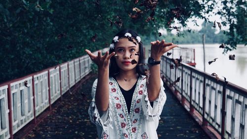 Woman throwing leaves while standing on bridge