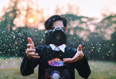Man throwing camera amidst confetti