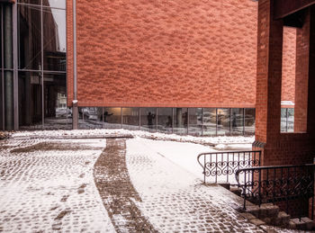 Snow covered footpath by buildings in city