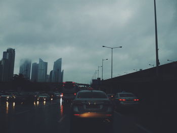 Traffic on road against cloudy sky