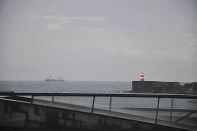 Lighthouse by sea against sky