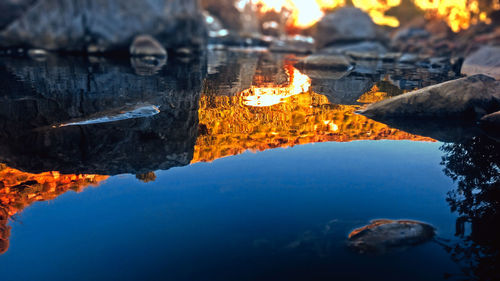 Reflection of rocks in lake against sky
