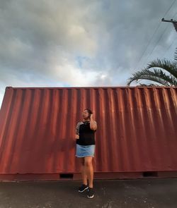 Full length of woman standing against cargo container