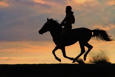 Silhouette man riding horse