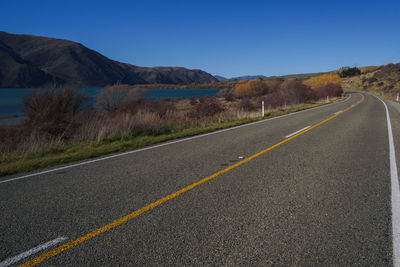 Road by mountains against clear sky