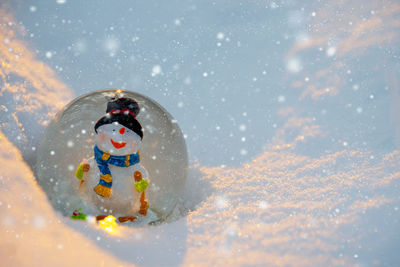 Glass snowball with snowman in the snow. winter concept. christmas and new year card