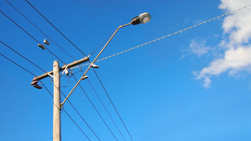 Low angle view of electricity pylon against blue sky