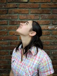 Young woman standing against brick wall