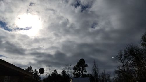 Low angle view of storm clouds over silhouette trees