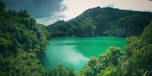 Scenic view of emerald green lake with mountains against sky - thailand