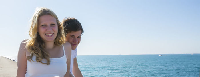 Portrait of young woman standing against sea