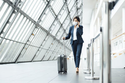 Female professional talking on smart phone while walking in corridor during pandemic