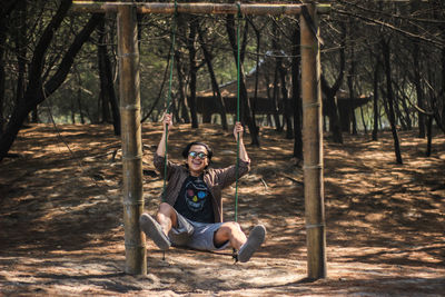 Portrait of young man sitting playing on swing