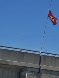 Low angle view of flag against clear blue sky