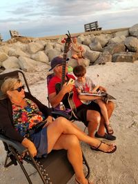 Grandparents sitting with grandson at beach during sunset