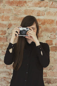 Midsection of woman photographing against wall