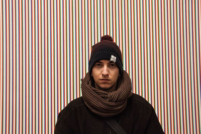 Portrait of hipster man wearing warm clothing against patterned wall